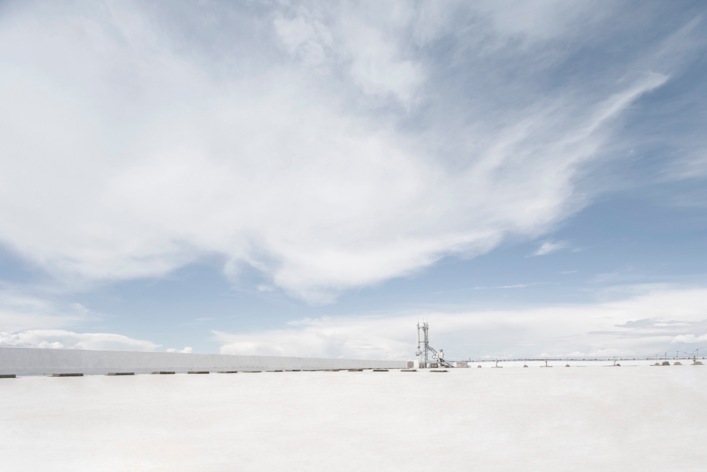 Picturepool Studios rooftop — rooftop surface beneath dramatic wispy cirrus clouds, with a distant telecom antenna on the skyline