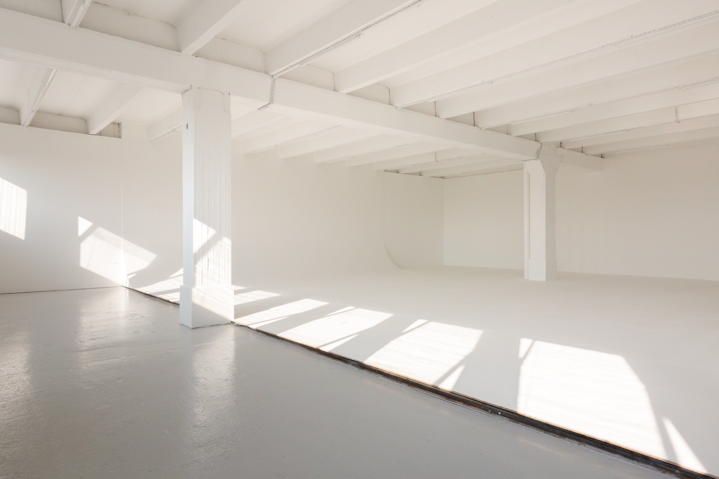 Picturepool Studios interior — bright white studio with exposed ceiling beams, concrete floor, natural light through windows and infinity cove
